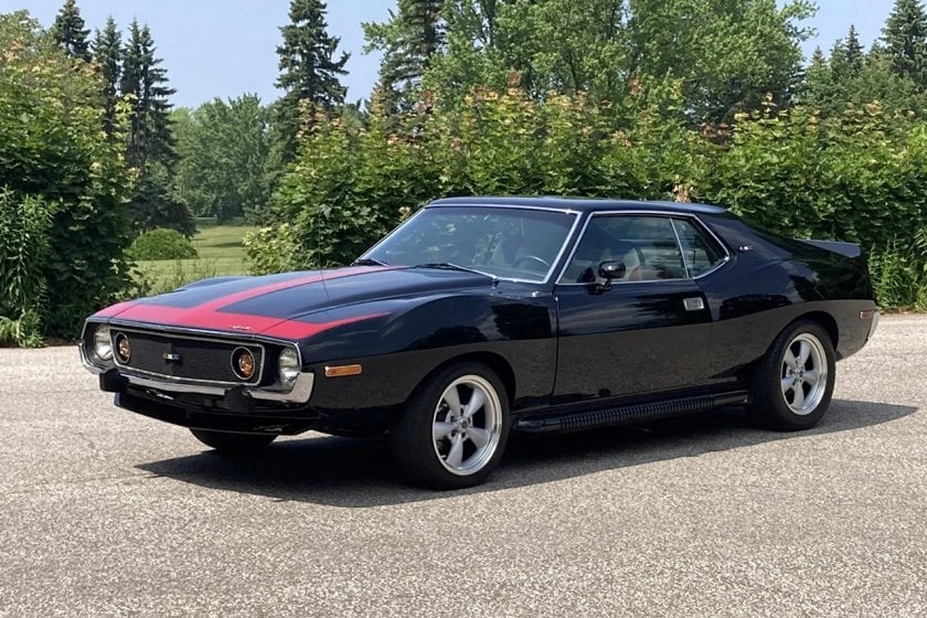 Black and red AMC Javelin parked infront of some trees