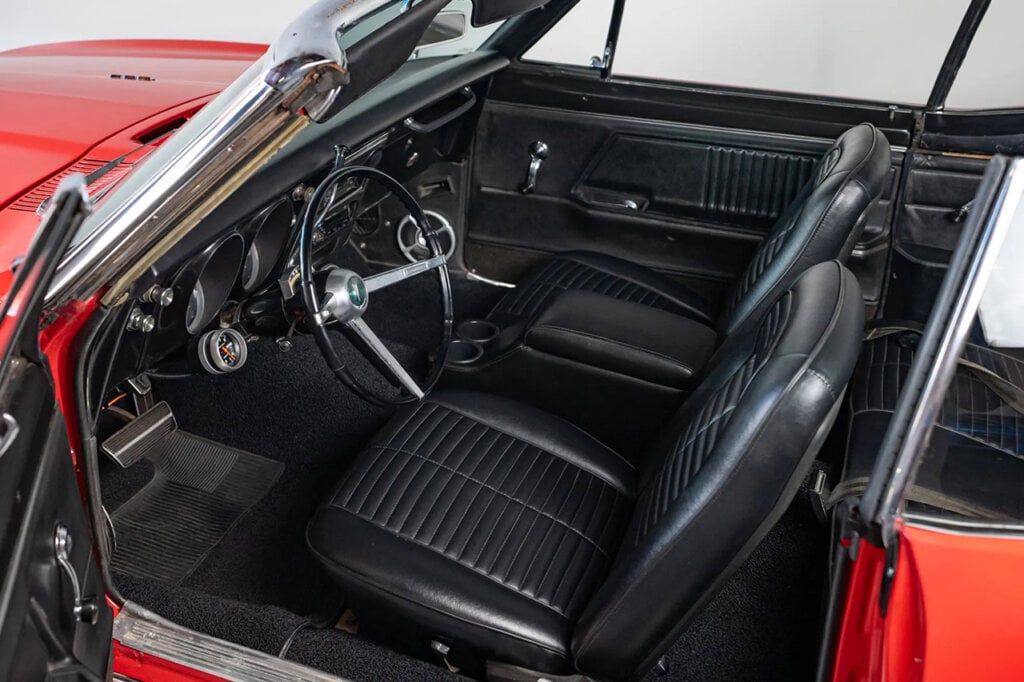 Red Pontiac Firebird's black leather interior showing a thin steering wheel and convertible top