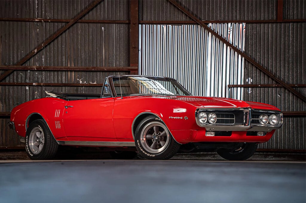 Red Pontiac Firebird parked in a warehouse