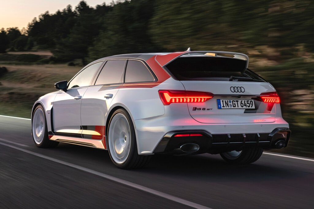 Rear shot of an Audi RS6 Avant driving on a freeway passing a cliffside with the sun setting