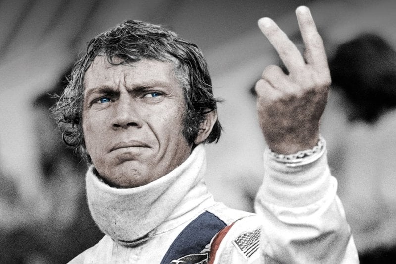 Actor Steve McQueen posing in a race suit