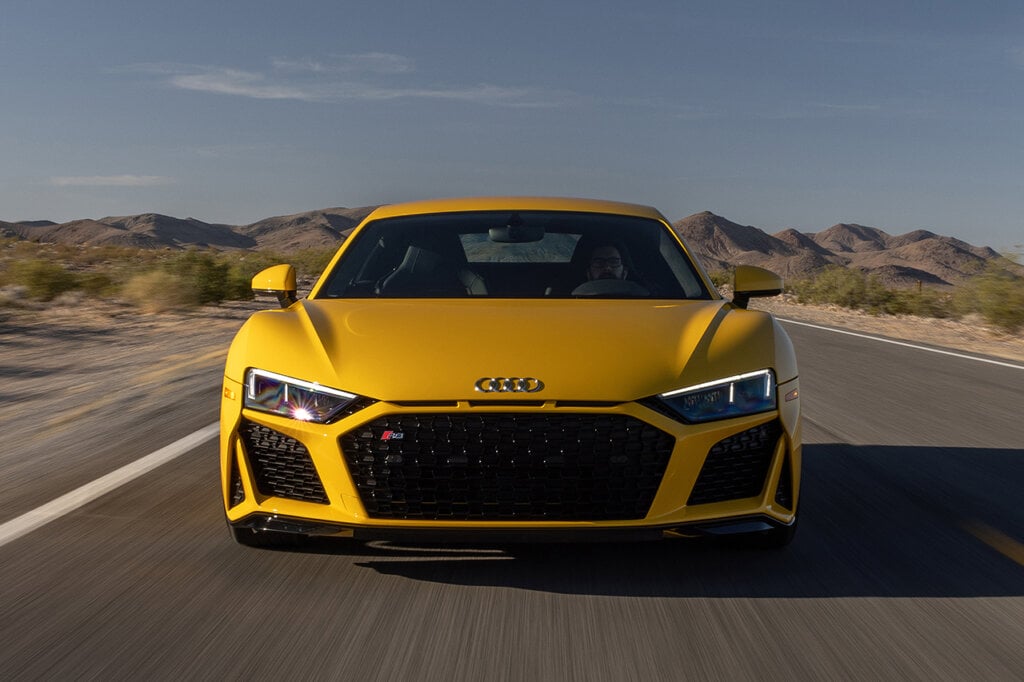 yellow audi driving fast on a freeway with a man driving it
