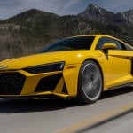 yellow audi R8 driving fast on road with mountains in background