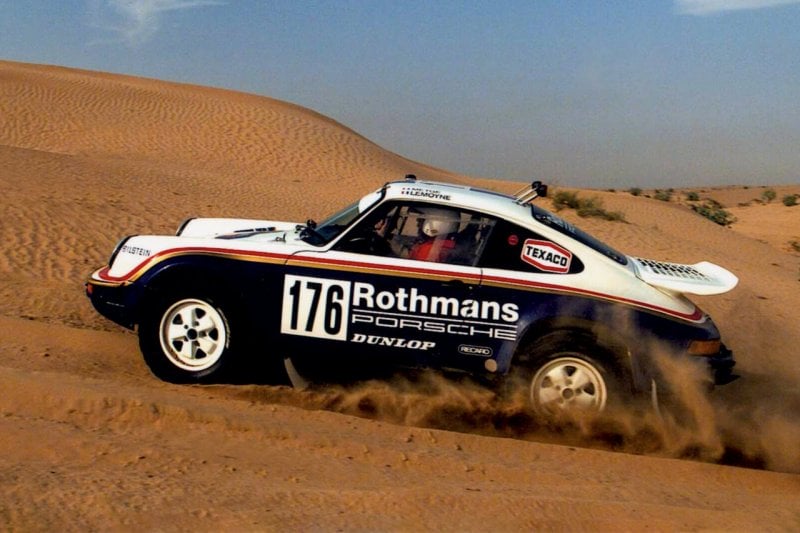 Dakar Porsche 953 rally race car with the number 176 on the door driving on the sand
