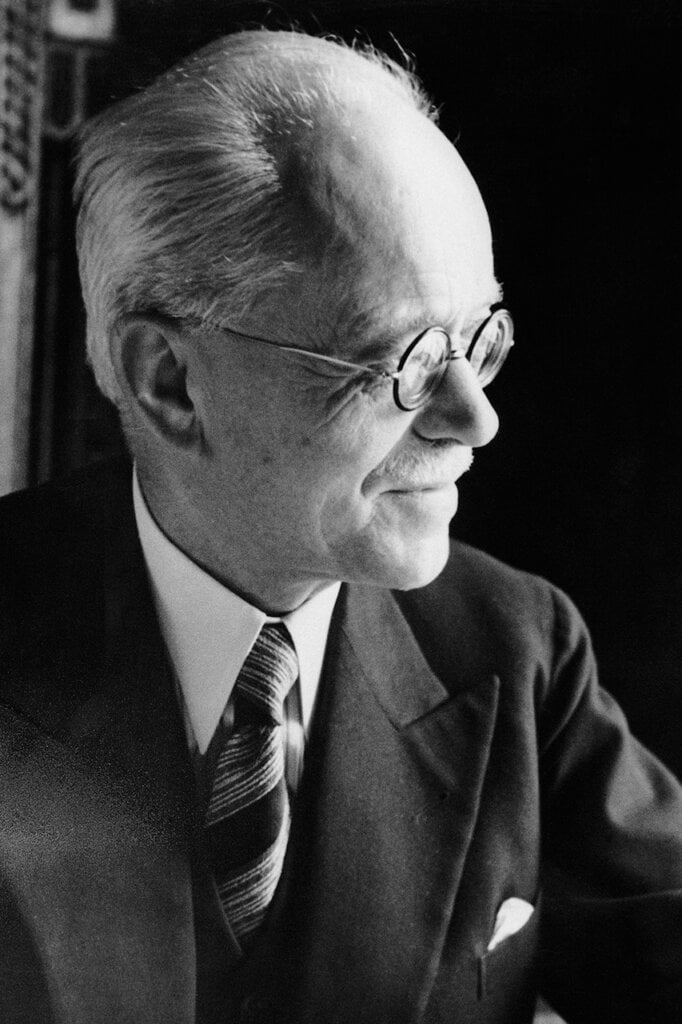 Black and white photo of a man in a suit with glasses looking to his left