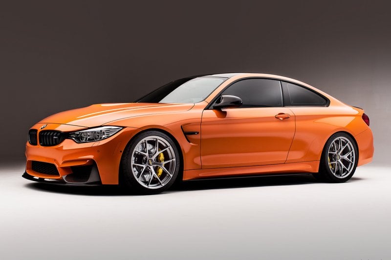 Orange BMW m3 pictured at an angle on silver wheels with a dark background