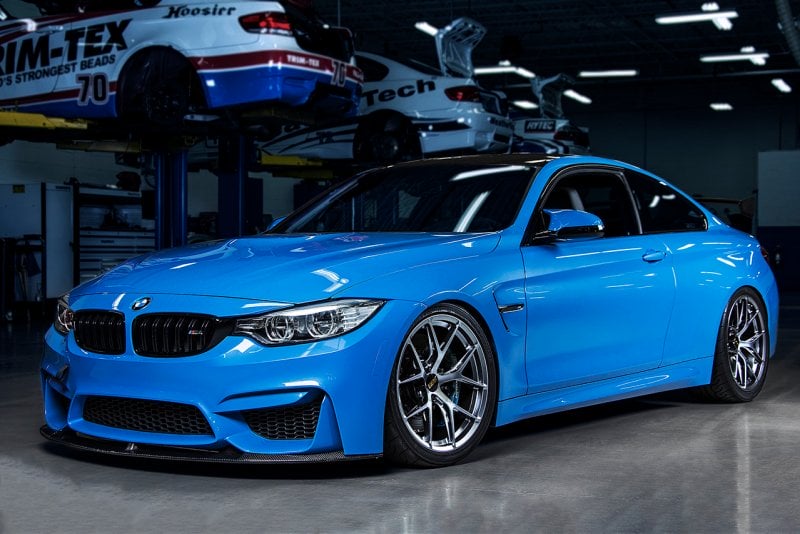 Blue BMW with BBS wheels in a garage with cars on lifts