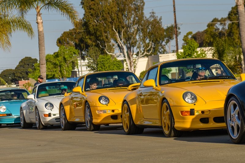 two yellow Porsche 911s parked behind one another in a line