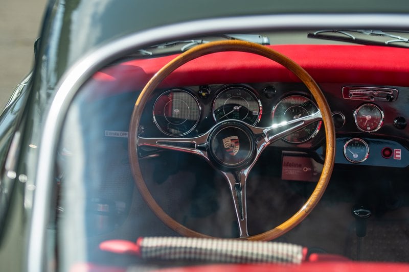 Porsche steering wheel on a grey car with red interior