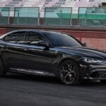 Black Alfa Romeo Giuilia Quadrifoglio Super Sport parked on a racetrack with empty stands behind it
