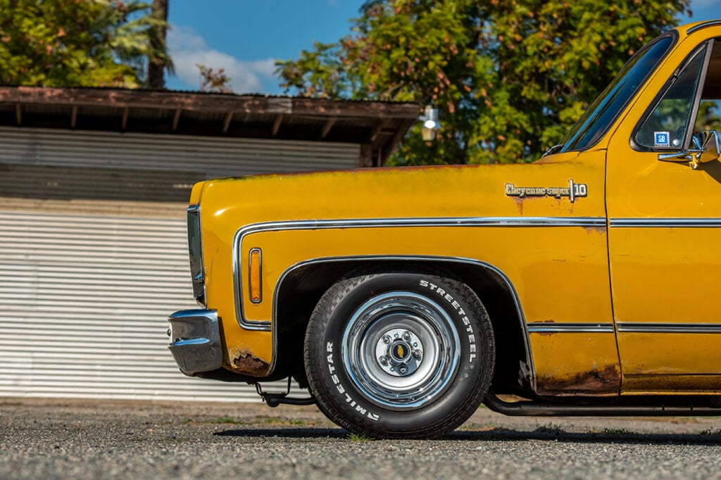 Yellow Cheyenne C10 truck with a chrome wheel. Garage door in background