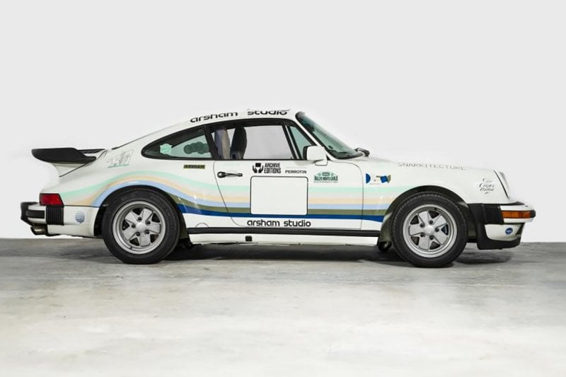 side profile shot of Porsche 930A 911 with a livery on it next to a white wall