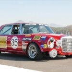 red modified Mercedes car on racetrack with many decals covering the car