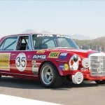 red modified Mercedes car on racetrack with many decals covering the car