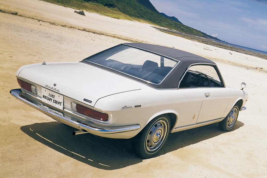 white Mazda luce parked on a beach