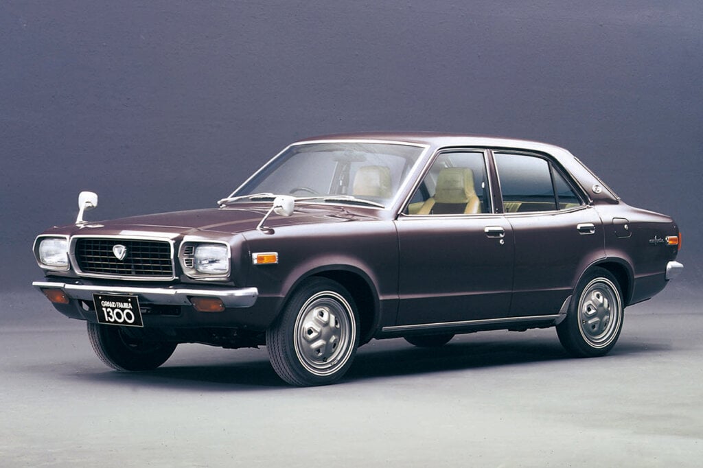 brown Mazda grand familia parked in a room with a solid color background behind it