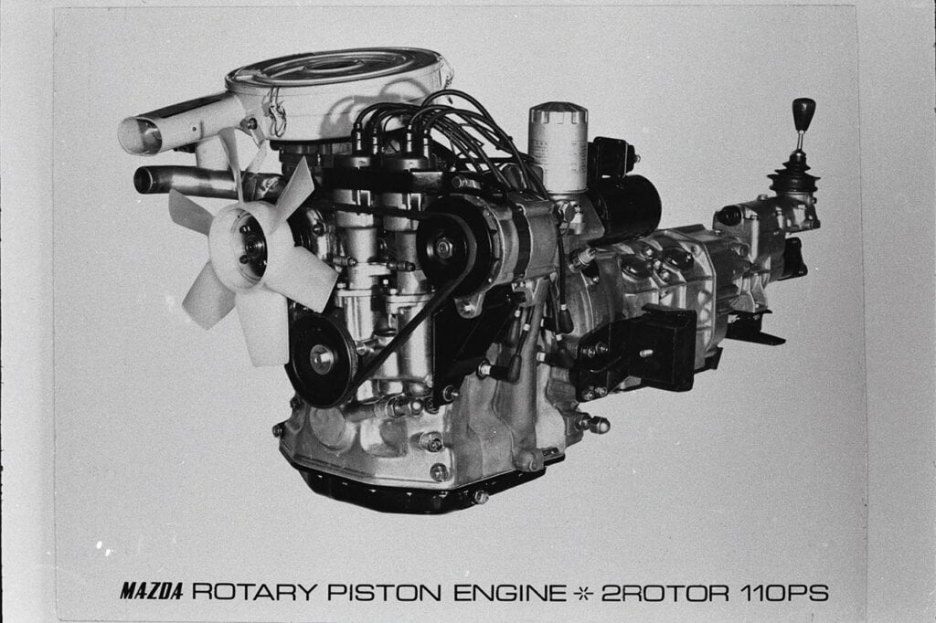 black and white photo of wankel rotary engine attached to transmission with written caption below it