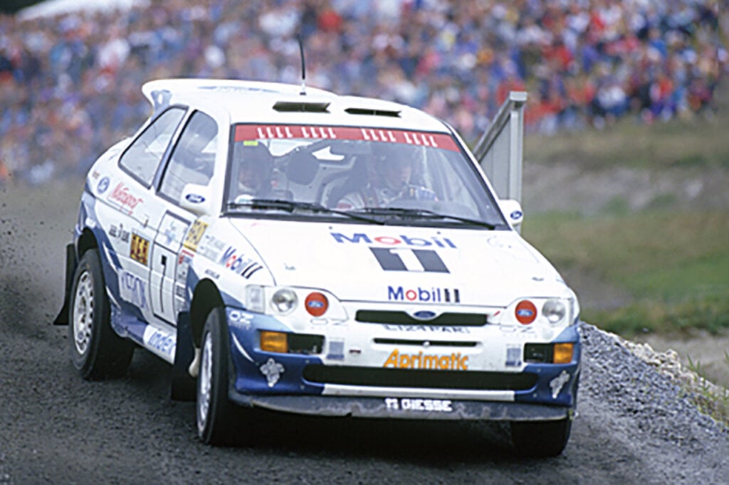 White and blue Ford Escort Cosworth driven by a race car driver
