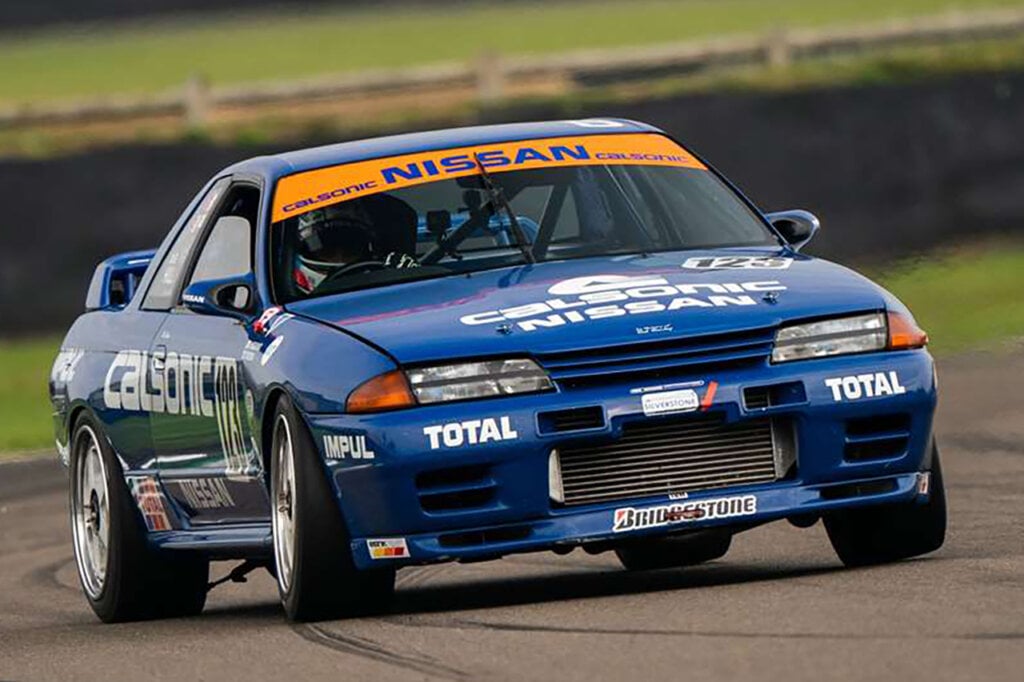 Blue Calsonic GTR R32 with a yellow banner on a racetrack