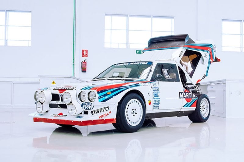 white Lancia Delta S4 parked in a stark white room with the rear open