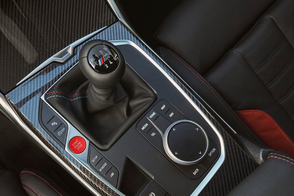 center console with BMW brand stick shift with carbon fiber elements and leather seats around it