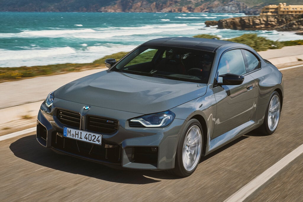Grey BMW M2 driving passed the ocean and beach
