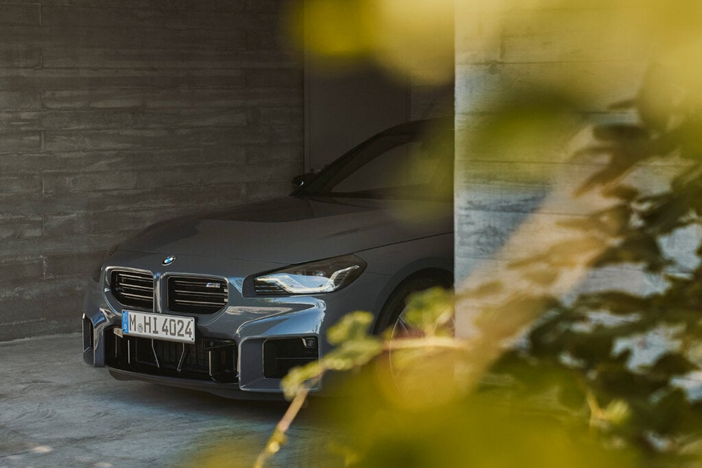 Grey BMW parked in a private garage with trees in foreground