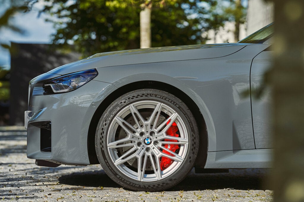 BMW M2 silver alloy wheel parked on a stone driveway