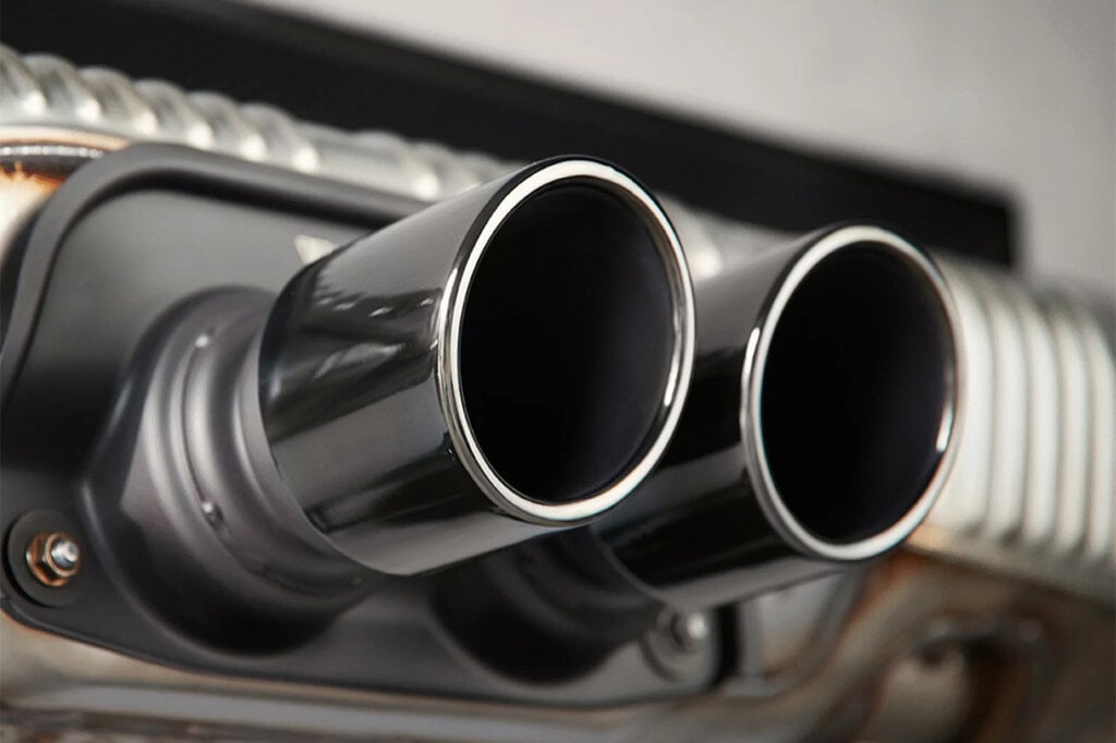Two exhaust tips with metal ridges on the panel behind these